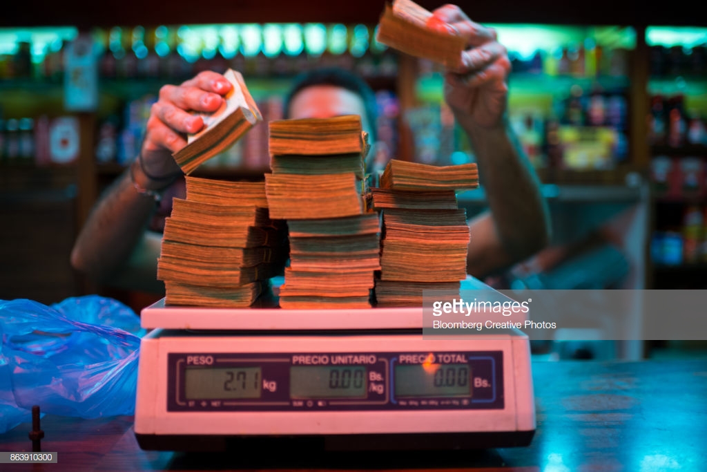 A manager weighs banknotes on a scale at a bakery in Venezuela.